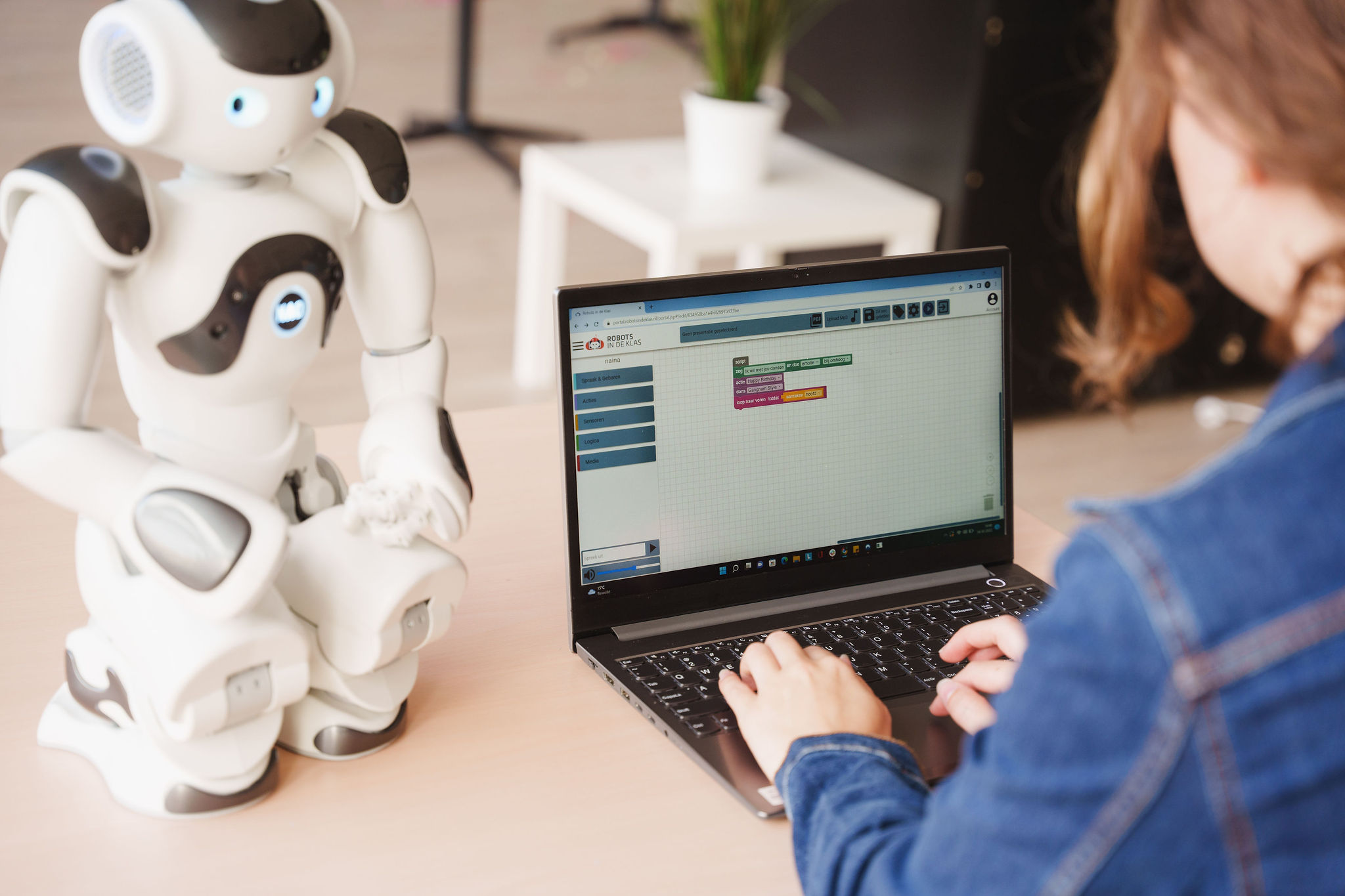 vrouw programmeert robot assistent op de laptop